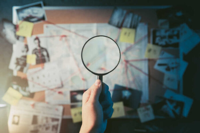 Detective,Hand,Holding,A,Magnifying,Glass,In,Front,Of,A