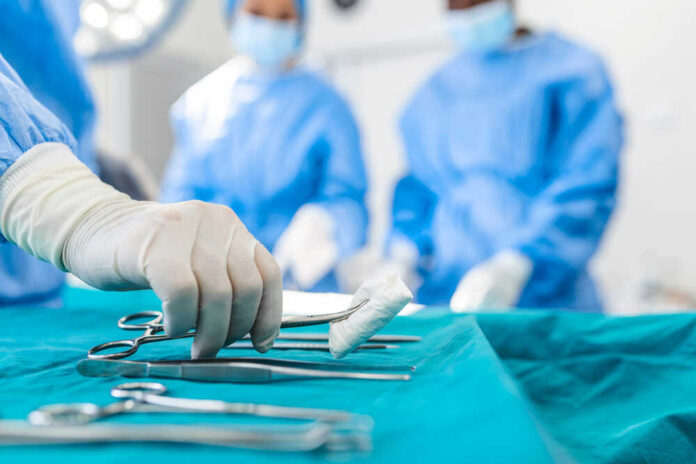 Nurse,Hand,Taking,Surgical,Instrument,For,Group,Of,Surgeons,At