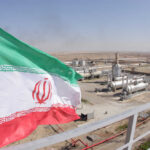 Iran’s Eye-Popping Offer: Sanctions Relief or Bust Iranian flag waving in front of an oil processing facility
