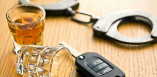 Handcuffs, car key, and whiskey on table.