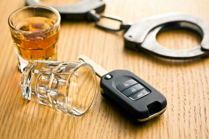 41249979 Handcuffs, car key, and whiskey on table.