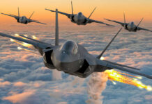 Four fighter jets flying above clouds, firing flares.