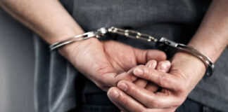 Person handcuffed with hands behind back.