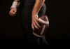 Football player holding a football in hand.