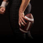 Football player holding a football in hand.