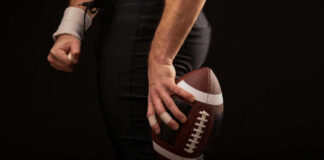 Football player holding a football in hand.
