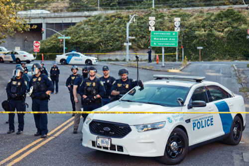 dhs-ice-police1143336608 Police officers standing by patrol car and barricade tape