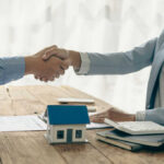 Two people shaking hands over a contract