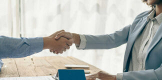 Two people shaking hands over a contract