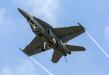 Military jet flying with vapor trails visible
