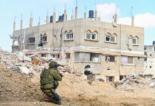 Soldier crouching near building in a wartorn area