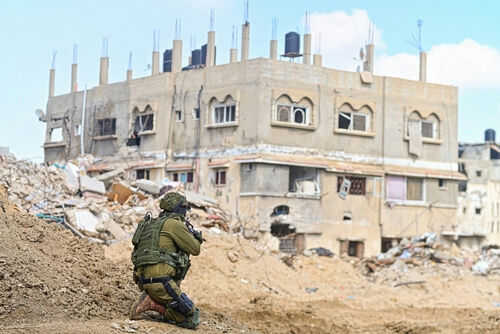Soldier crouching near building in a wartorn area