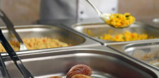 Buffet with sausages and yellow rice in trays.