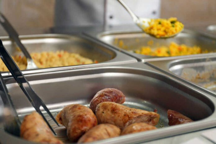 Buffet with sausages and yellow rice in trays.
