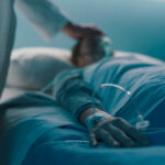 A medical professional attending to a patient in a hospital bed