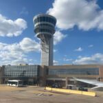 TSA Pay CRISIS: Trump’s Emergency Gamble View of an airport control tower and terminal from an airplane window