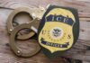 ICE Detentions Drift Beyond Court Limits, Again ICE officer badge next to handcuffs on a wooden surface