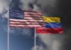 Flags of the United States and Venezuela waving against a cloudy sky