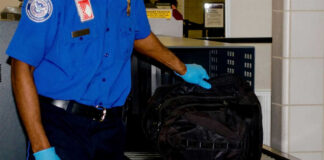 Security worker inspecting black bag on conveyor belt