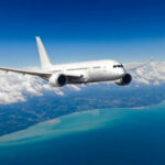 Airplane flying over coastline and clouds in sky