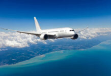 Airplane flying over coastline and clouds in sky