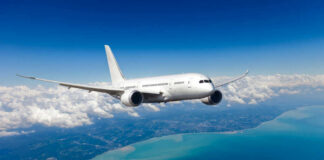Airplane flying over coastline and clouds in sky