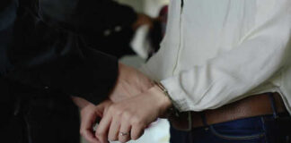 Person being handcuffed by someone in black clothing