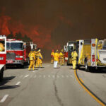 Firefighters battling large wildfire with fire trucks present