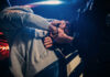 Police officer handcuffing person near a car
