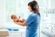 Nurse holding a newborn baby in a hospital.