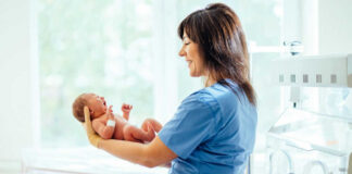 Nurse holding a newborn baby in a hospital.
