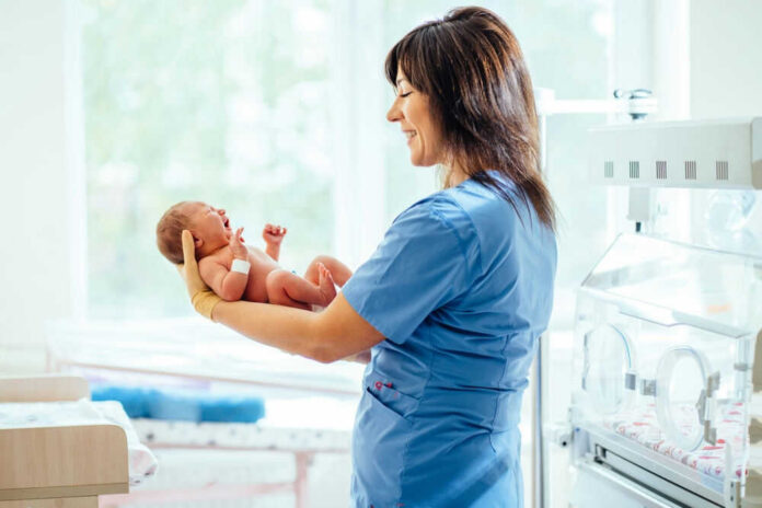 Nurse holding a newborn baby in a hospital.