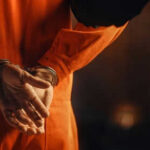 Cop-Turned-Threat: Racial Massacre Averted Person in orange jumpsuit with hands cuffed behind back