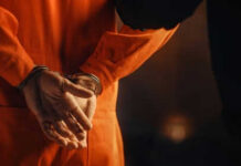 Person in orange jumpsuit with hands cuffed behind back