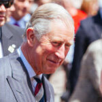 A smiling man in formal attire interacting with a crowd