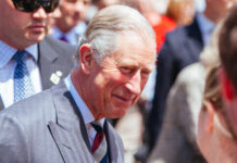 A smiling man in formal attire interacting with a crowd