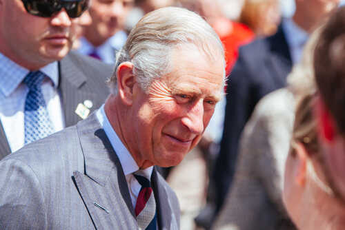 A smiling man in formal attire interacting with a crowd