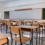 An empty classroom with wooden desks and a chalkboard