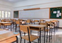 An empty classroom with wooden desks and a chalkboard