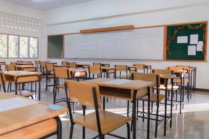 An empty classroom with wooden desks and a chalkboard