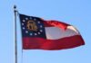 Georgia state flag waving against a clear blue sky