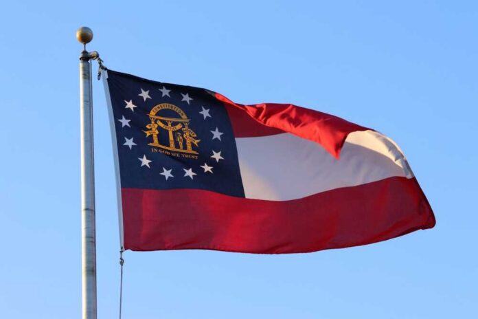 shutterstock_2352521509.jpg Georgia state flag waving against a clear blue sky