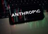 Smartphone displaying the word 'ANTHROPIC' over a background of financial graphs