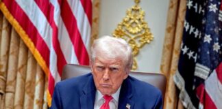 Donald Trump seated in the Oval Office with a serious expression