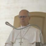 Pope seated on a throne with a microphone in front