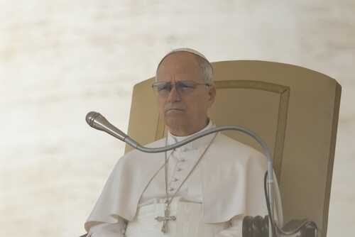 Pope seated on a throne with a microphone in front