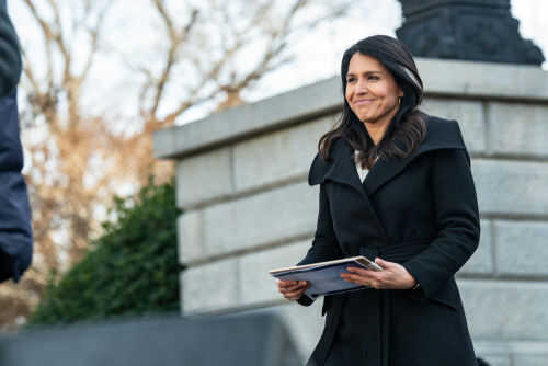 Person holding papers outdoors in a coat smiling