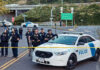 Police officers standing by patrol car and barricade tape