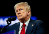 Media Historian SLAMS Trump-Colbert Feud man in suit and red tie speaking at a microphone