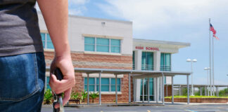 Person holding a handgun outside a high school building